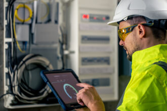Man, an electrical technician working in a switchboard with fuses. Installation and connection of electrical equipment.